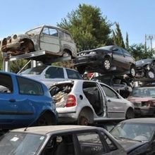 Un mucchio di auto sono accatastate una sopra l'altra in uno sfasciacarrozze.