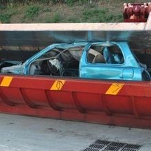 Un'auto blu è parcheggiata in un cassonetto rosso.