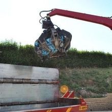 Una gru sta sollevando un oggetto di grandi dimensioni da un camion.