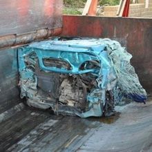 Un'auto blu è parcheggiata sul retro di un camion.