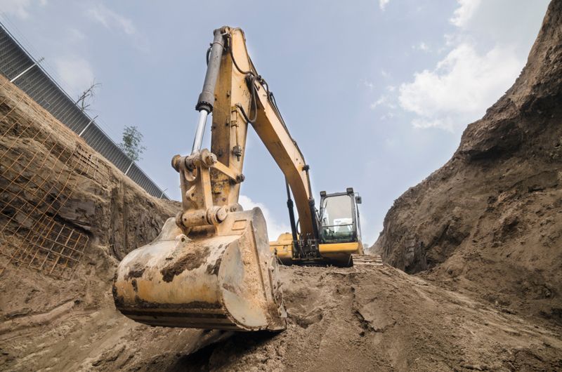 A yellow excavator is digging a hole in the ground.