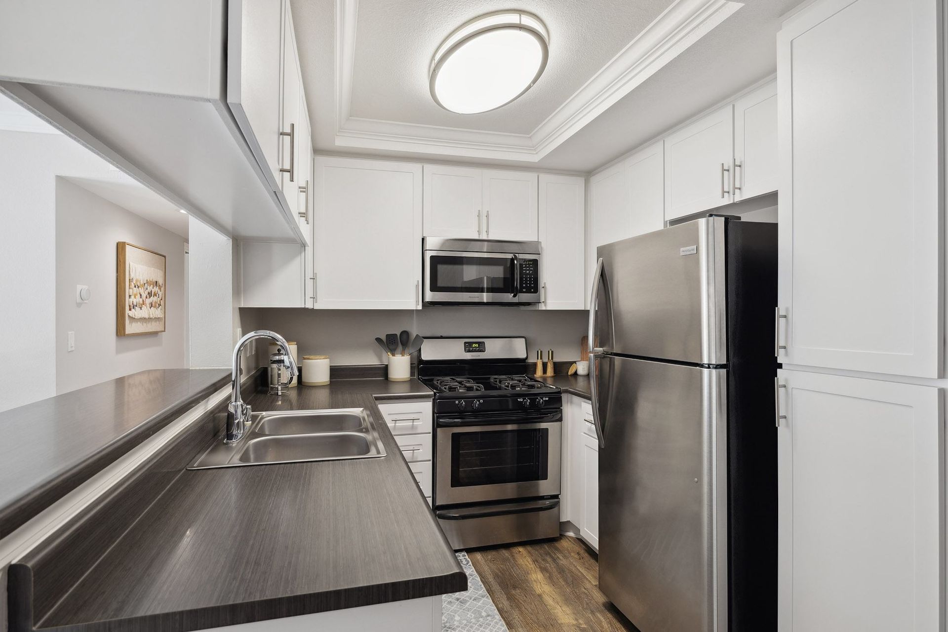 Modern galley kitchen with white cabinets and stainless-steel appliances.
