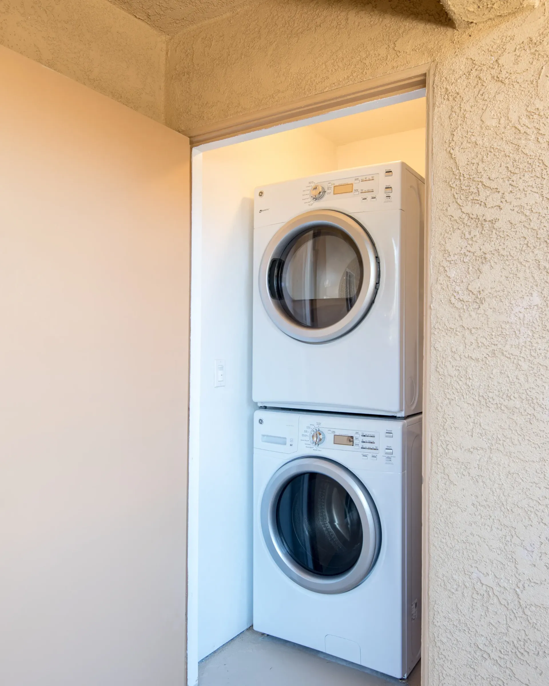 Stacked white washer and dryer in a small laundry closet.