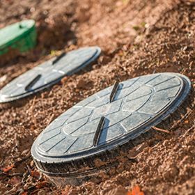 two septic tank lids are sitting in the dirt .