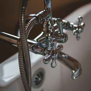 a close up of a bathtub faucet with a hose attached to it