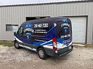 Conquer Plumbing & Air a blue and white company van is parked in front of a building .