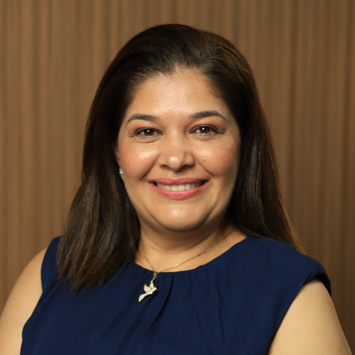 Uma mulher vestindo uma camisa azul e um colar está sorrindo para a câmera