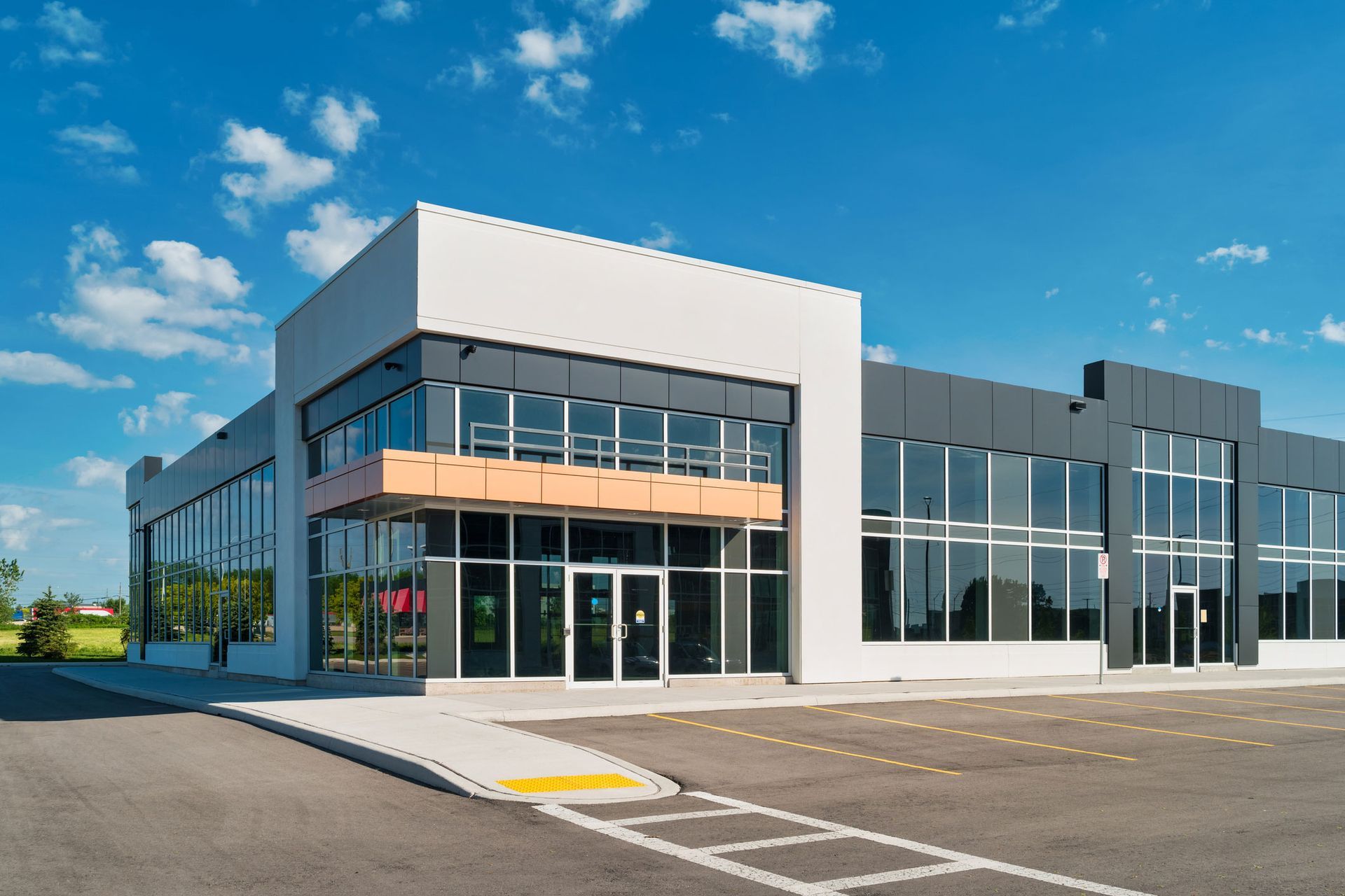 A large building with a lot of windows and a parking lot in front of it.