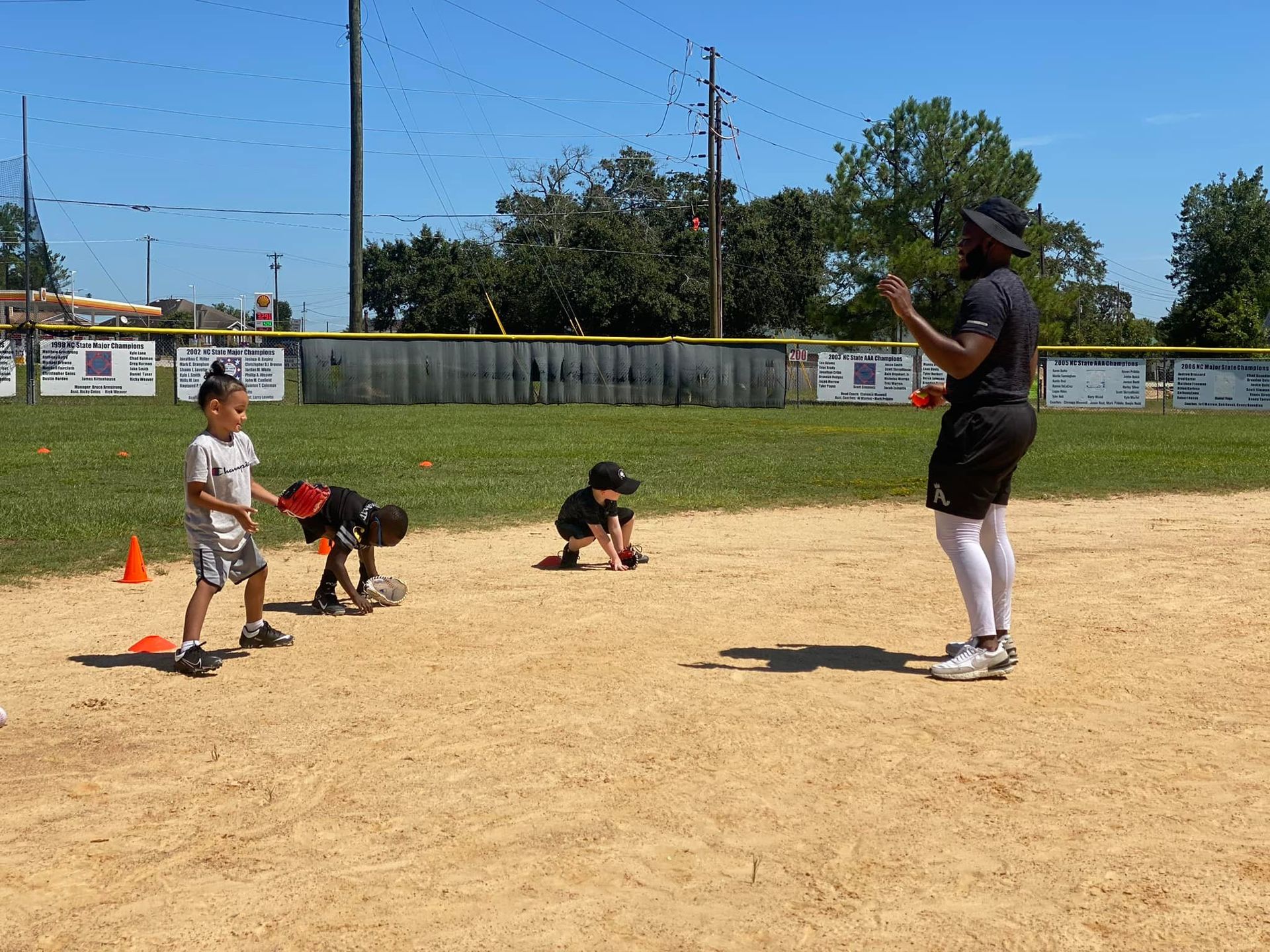 A man is standing on a baseball field talking to a group of young boys.