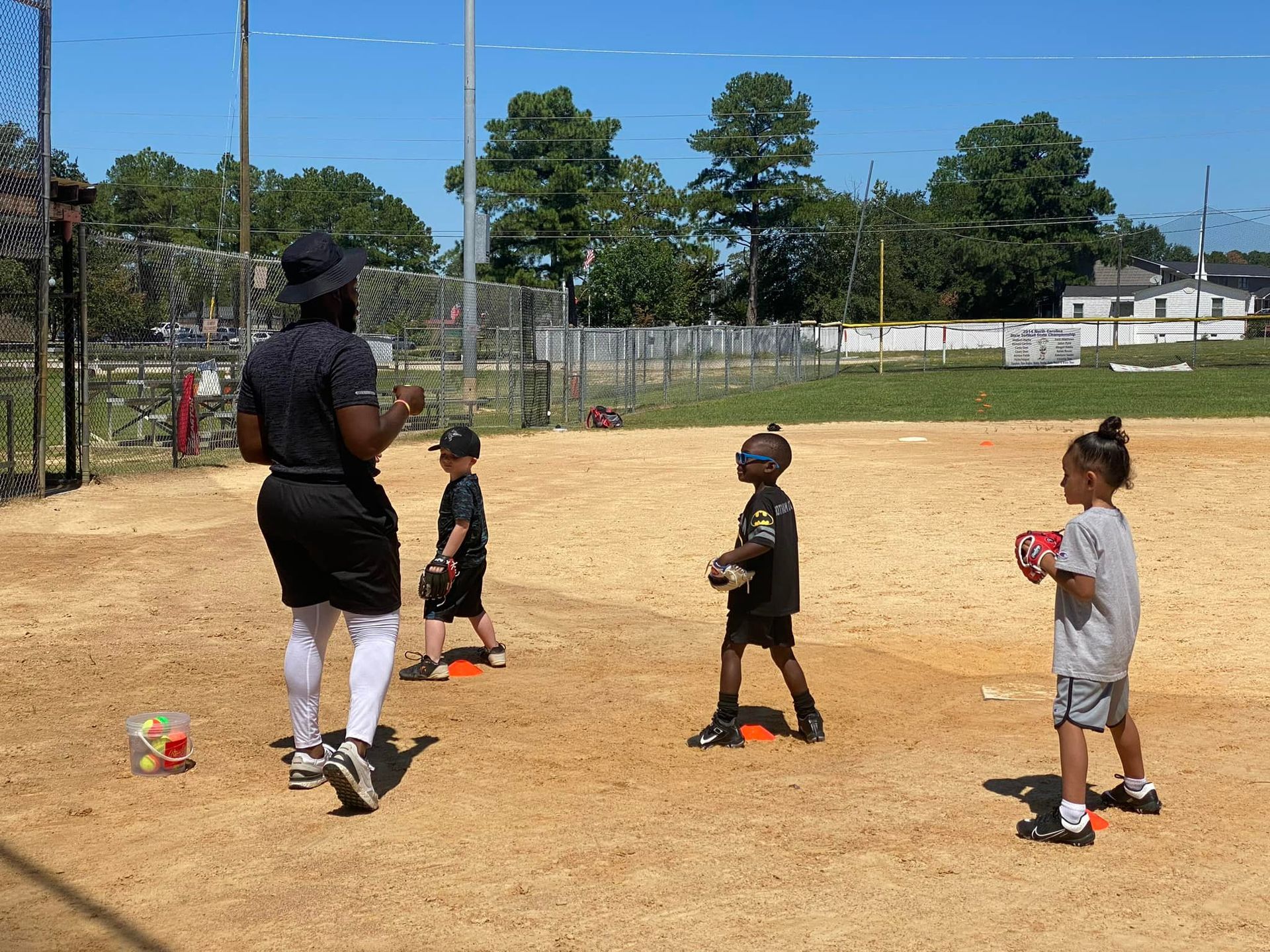 A group of young children are playing baseball on a dirt field.
