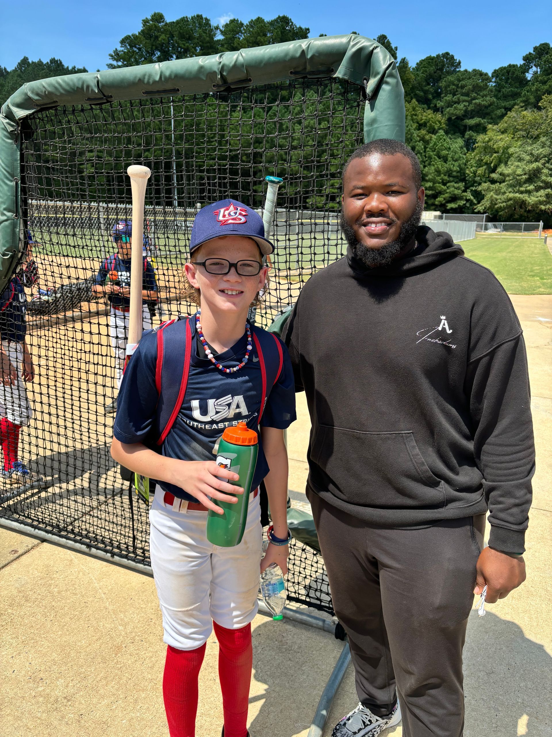 A man and a boy are standing next to each other on a baseball field.