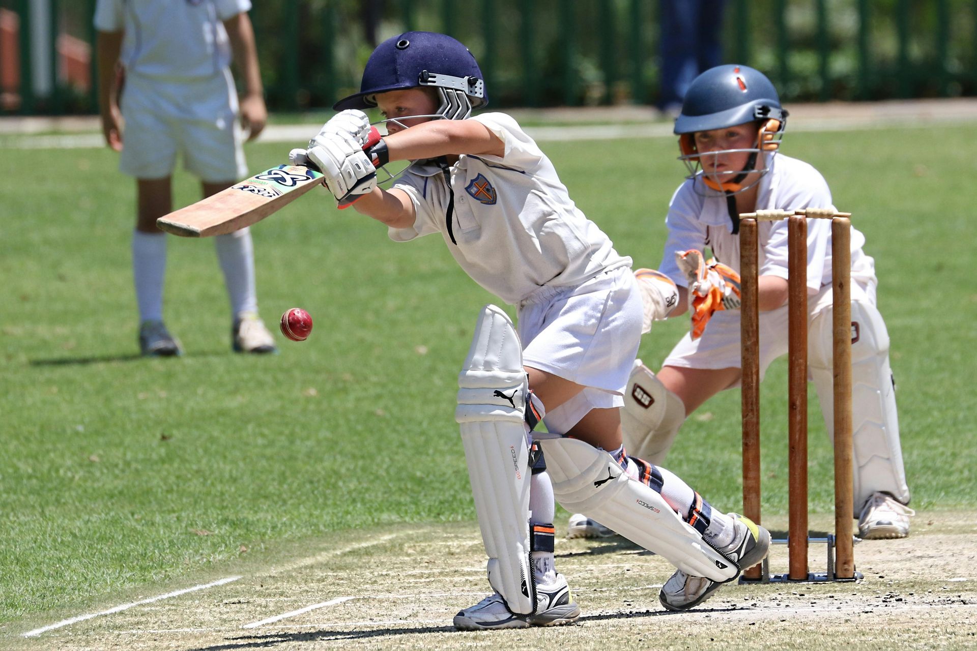 A young boy is playing a game of cricket on a field.