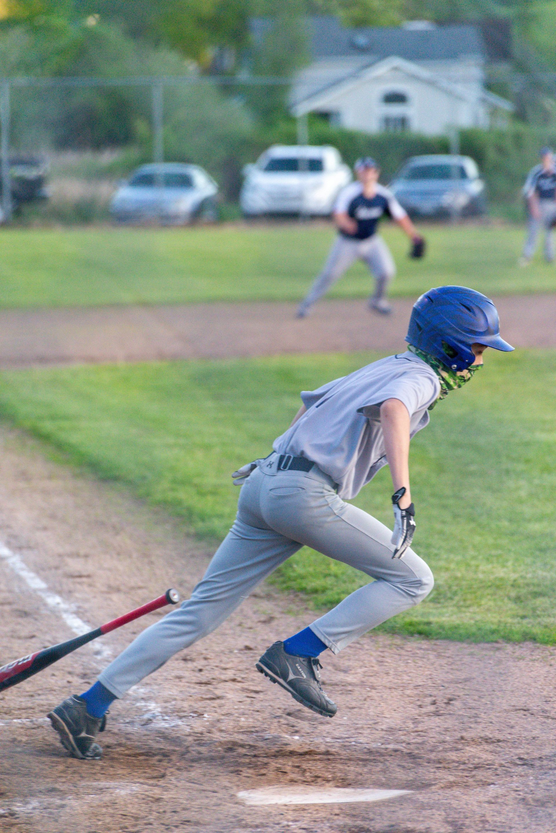 A young boy is running with a bat on a baseball field.