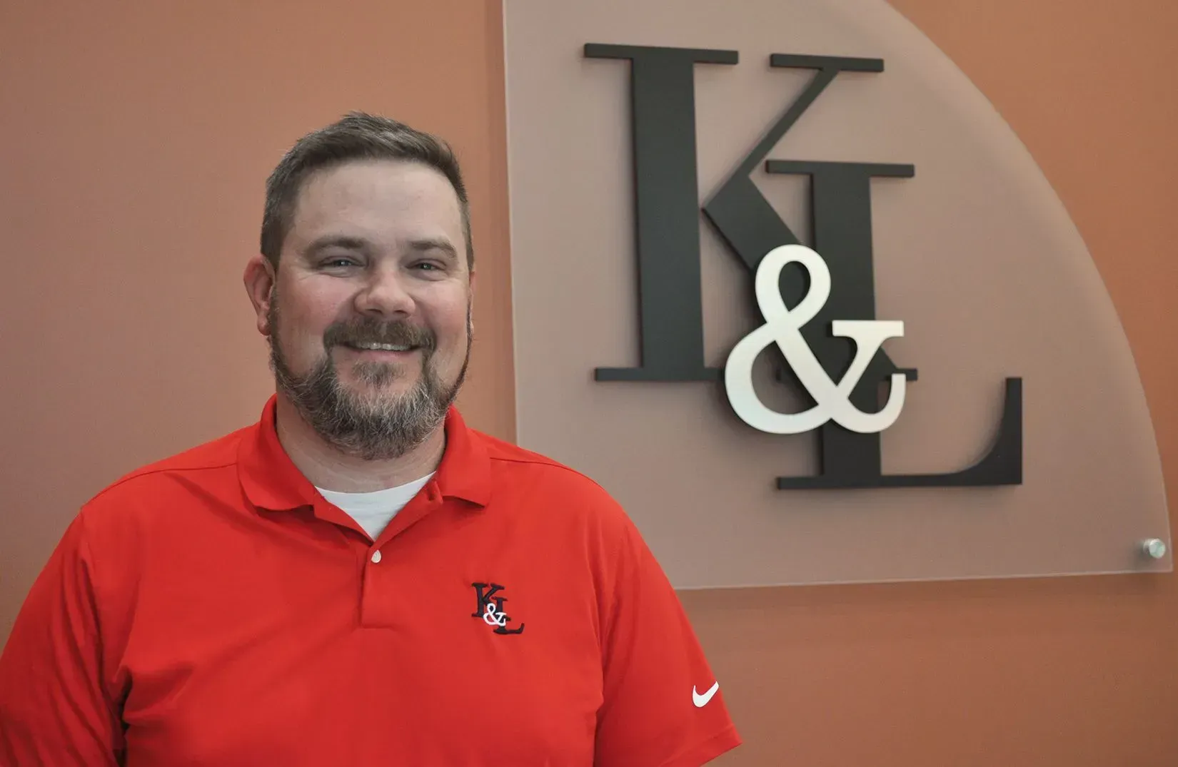 Man in red shirt stands in front of a sign with