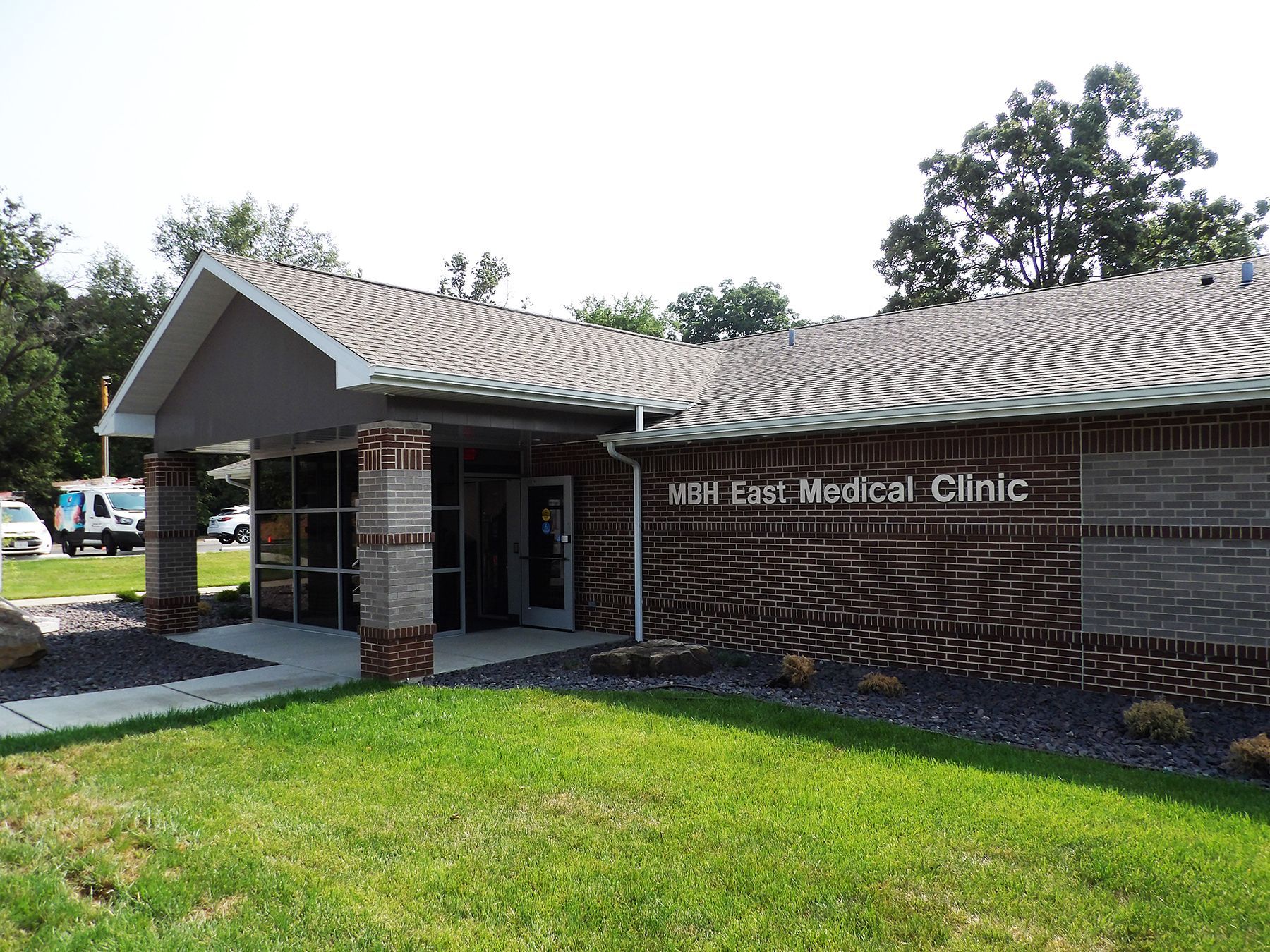 Exterior of VSH East Medical Clinic, brick and brown building with green lawn and landscaping.