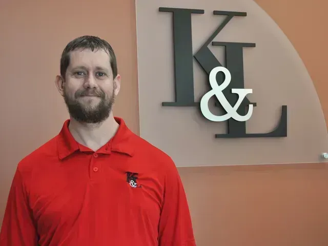 Man in red shirt stands in front of a wall with
