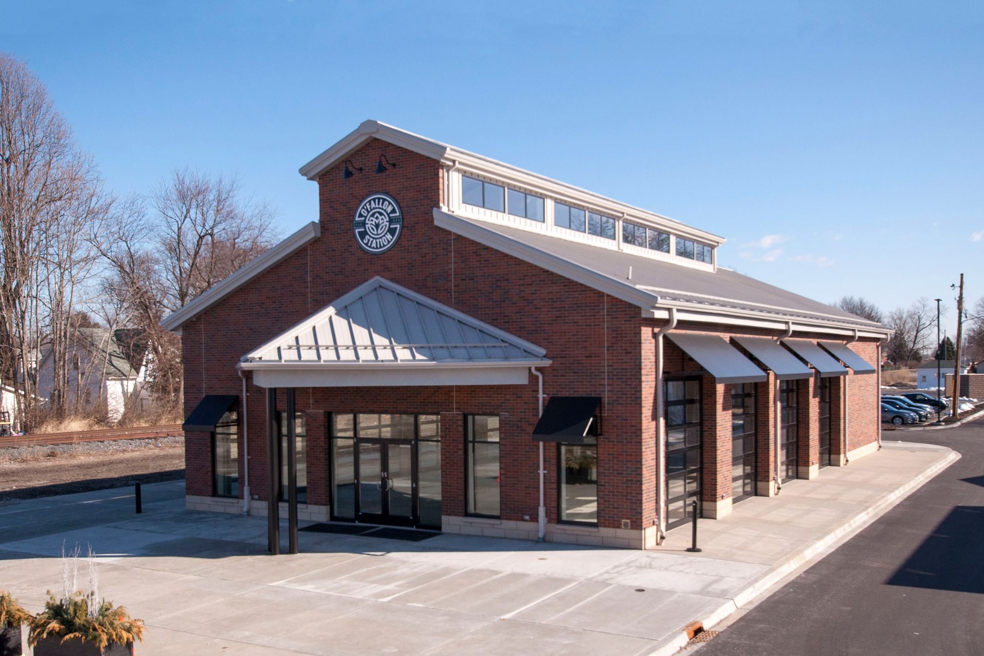 Brick building with clock, awning over entrance, windows, and black awnings over additional windows.