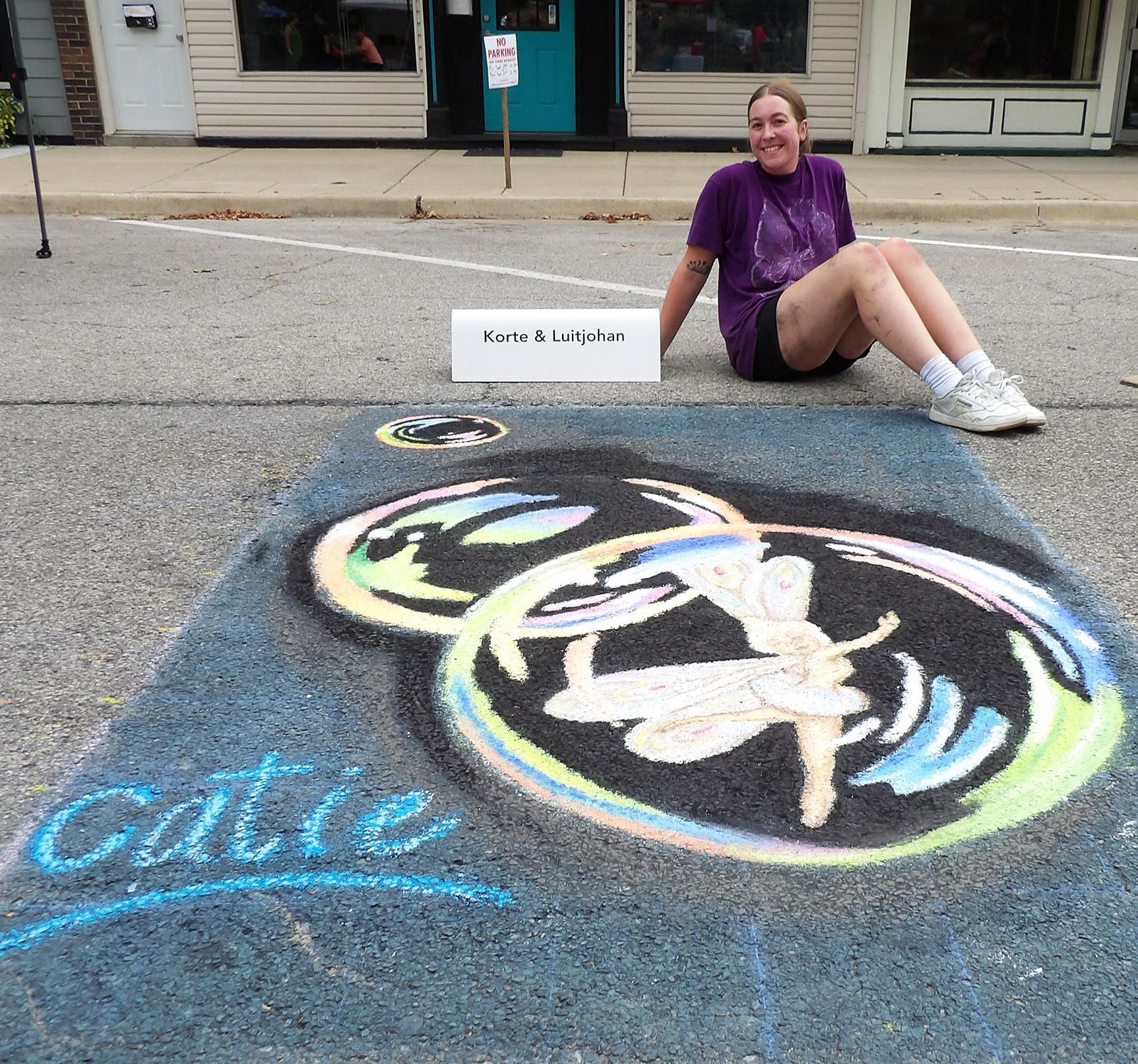 Three people holding boxes of donated items in front of a Christmas tree.