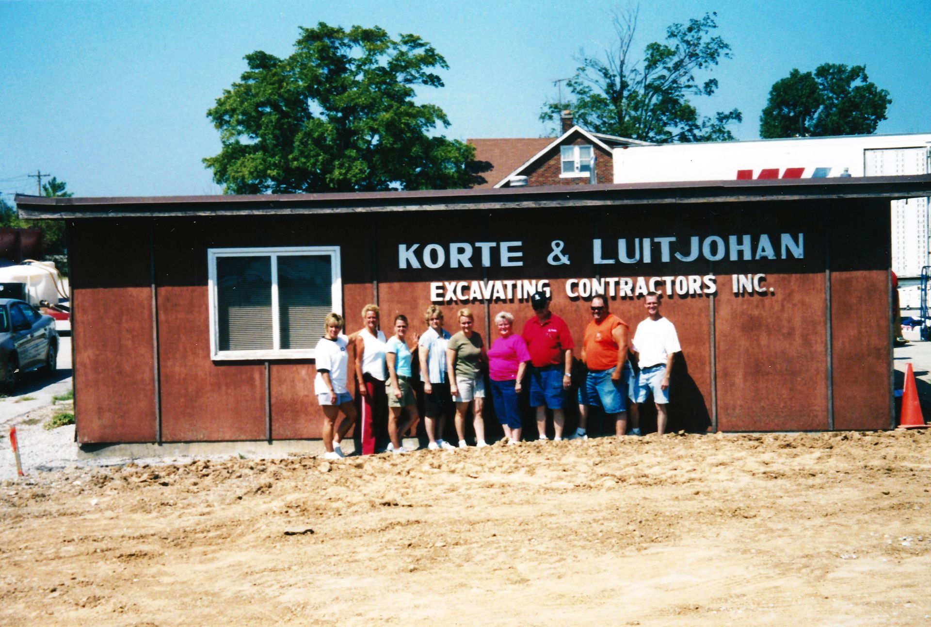 Two men digging in a dark earthen pit, one holding a tool, the other using a shovel.