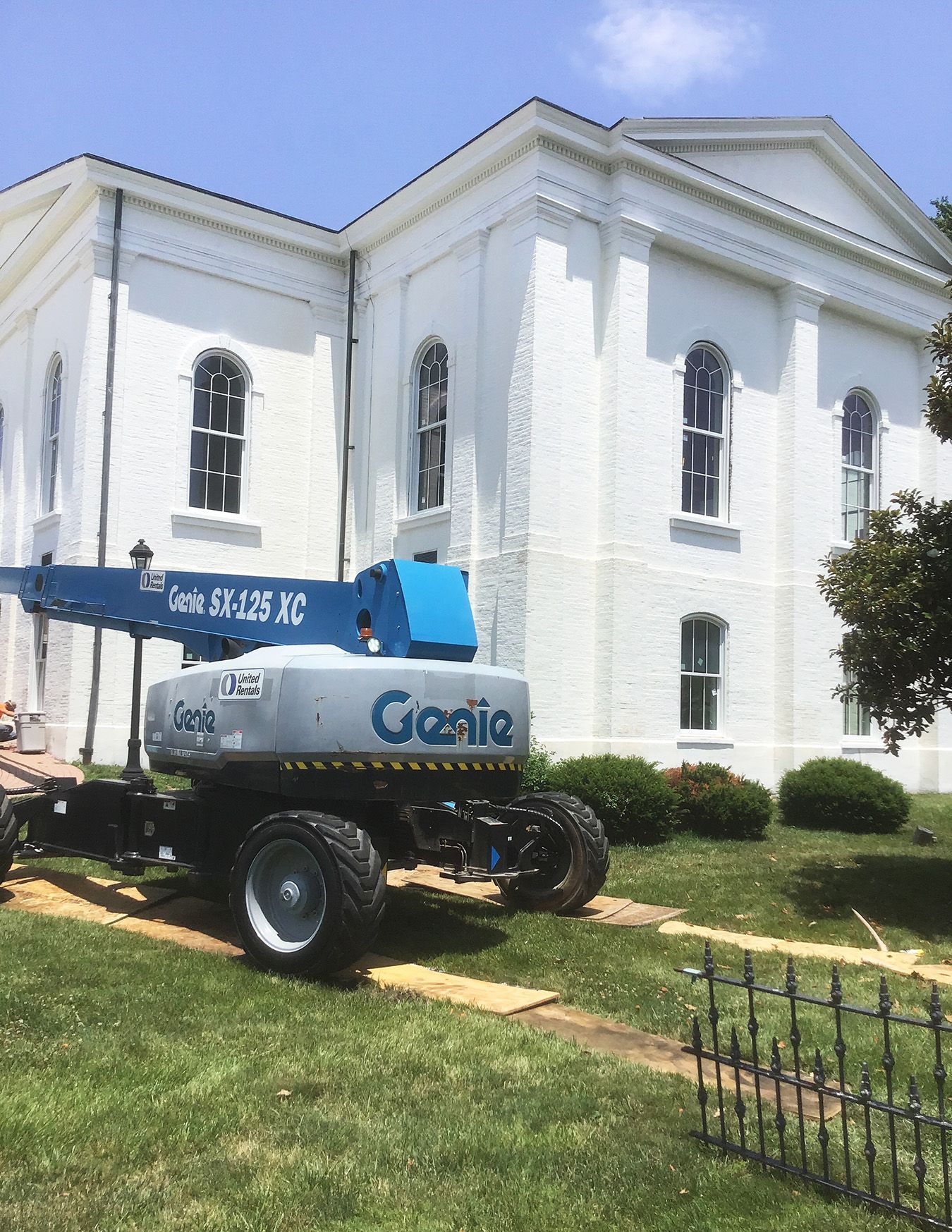 Interior with two wooden staircases flanking a doorway. A blue logo is on the floor.