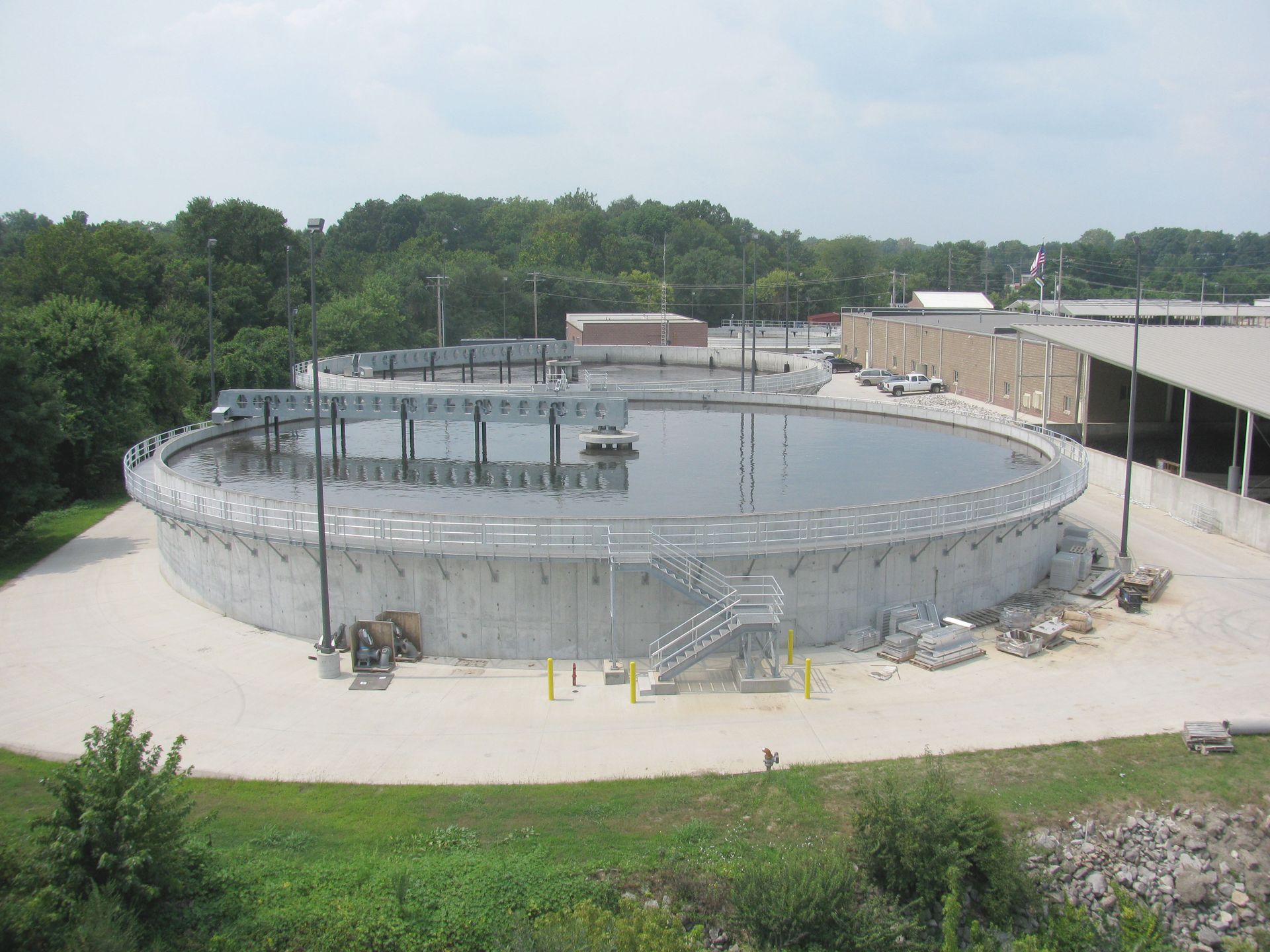 Large circular water treatment tanks, gray concrete, with surrounding structures.
