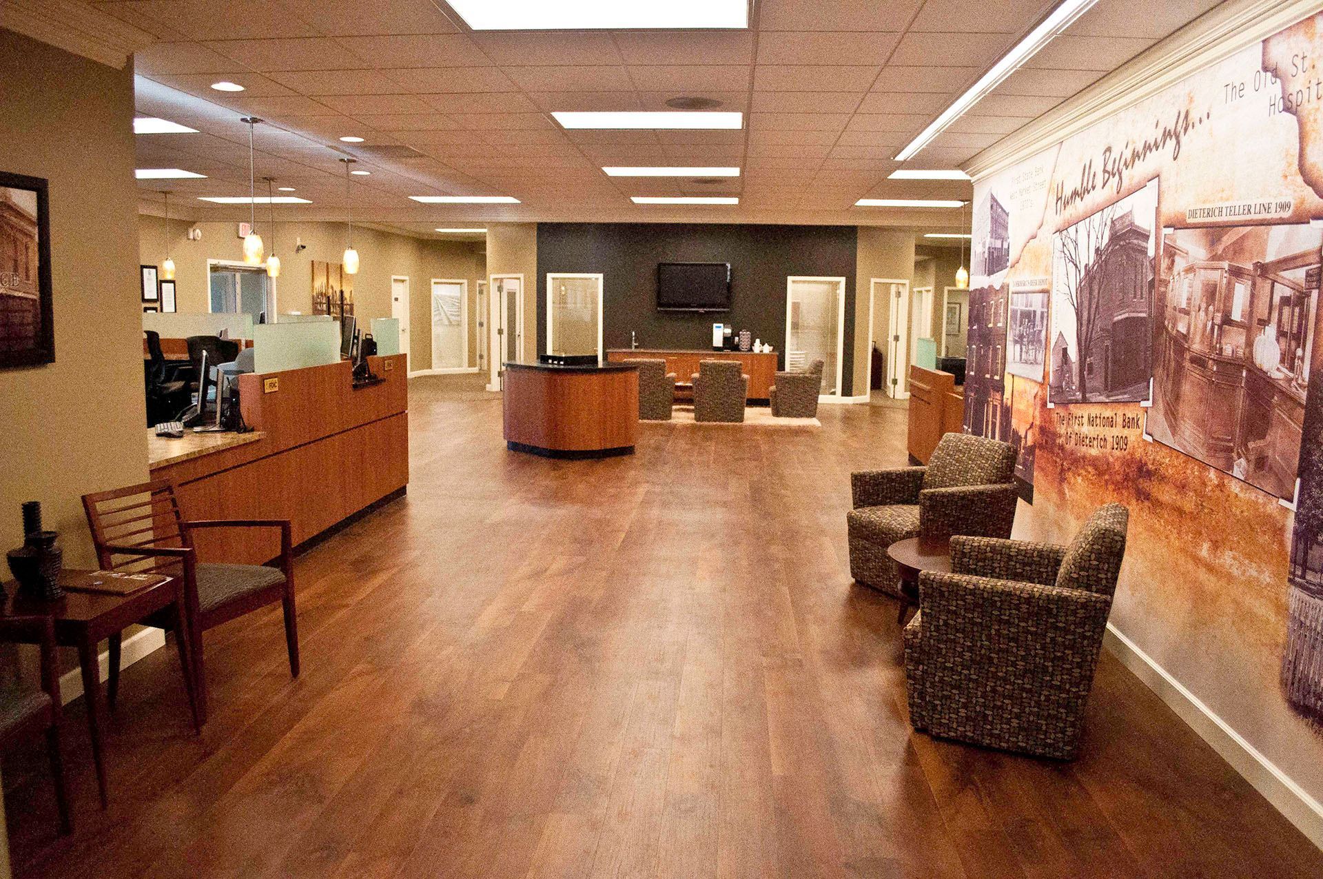Interior of a business with hardwood floors, seating areas, and a mural wall.