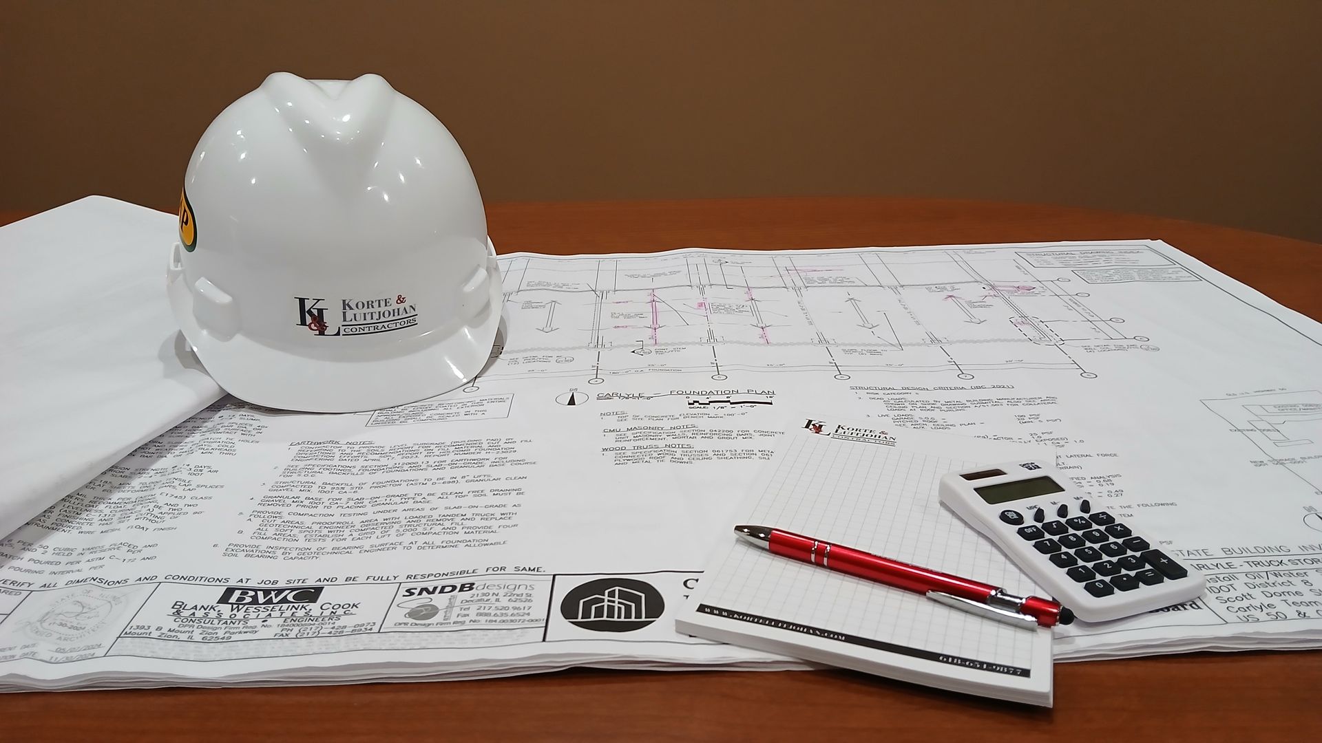 Concrete pumping truck near green trees and signs.