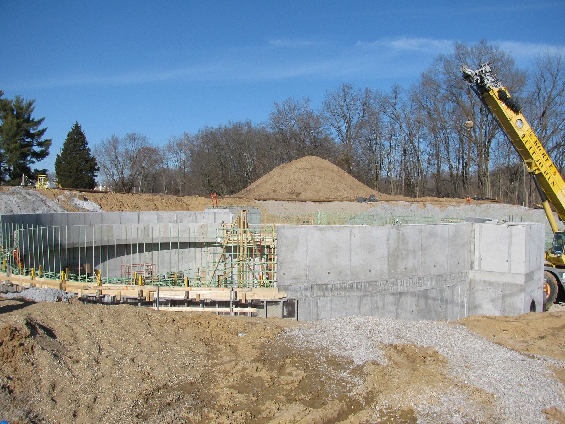 A blue cylindrical tank is lifted by a crane into a building under construction.