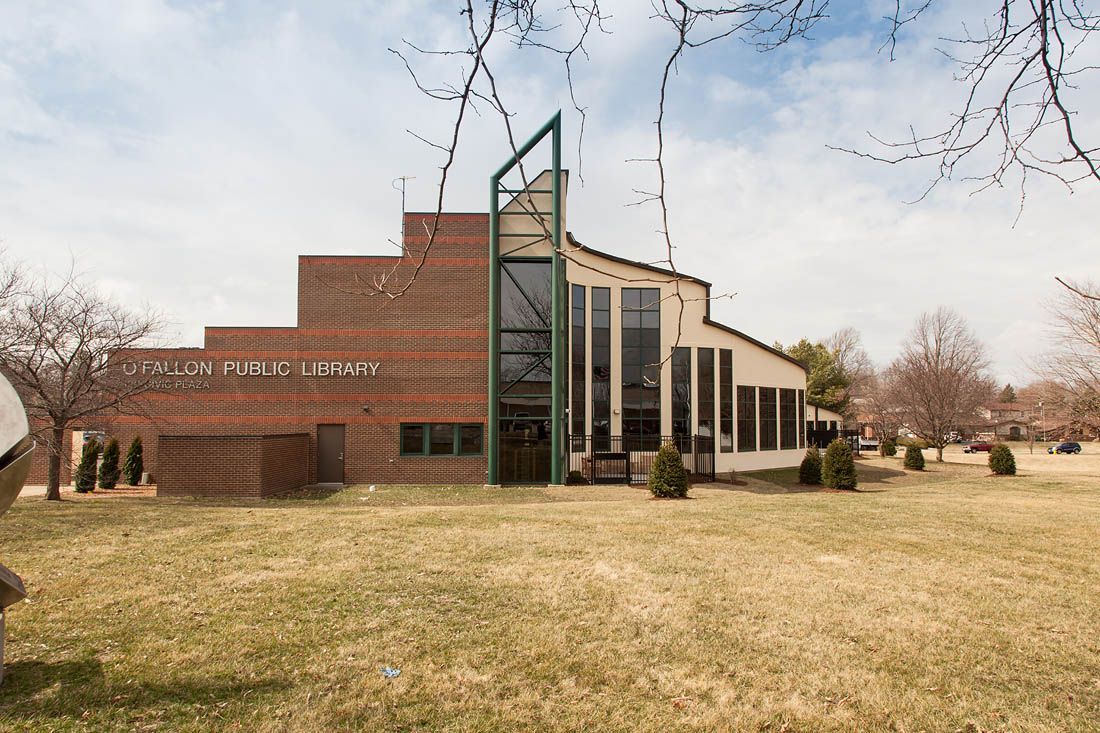 Brick building with a stepped facade and curved section with large windows, set on a grassy lawn.