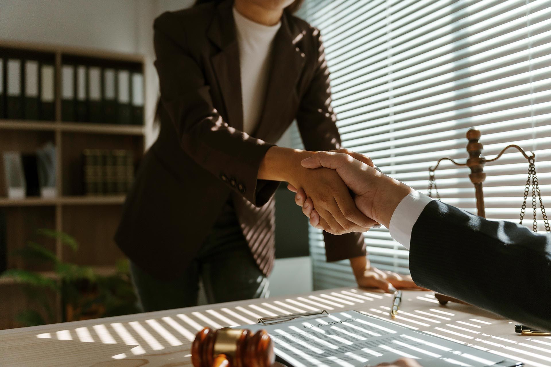 A family lawyer shakes hands with a client in their office after reaching an agreement in a lawsuit.