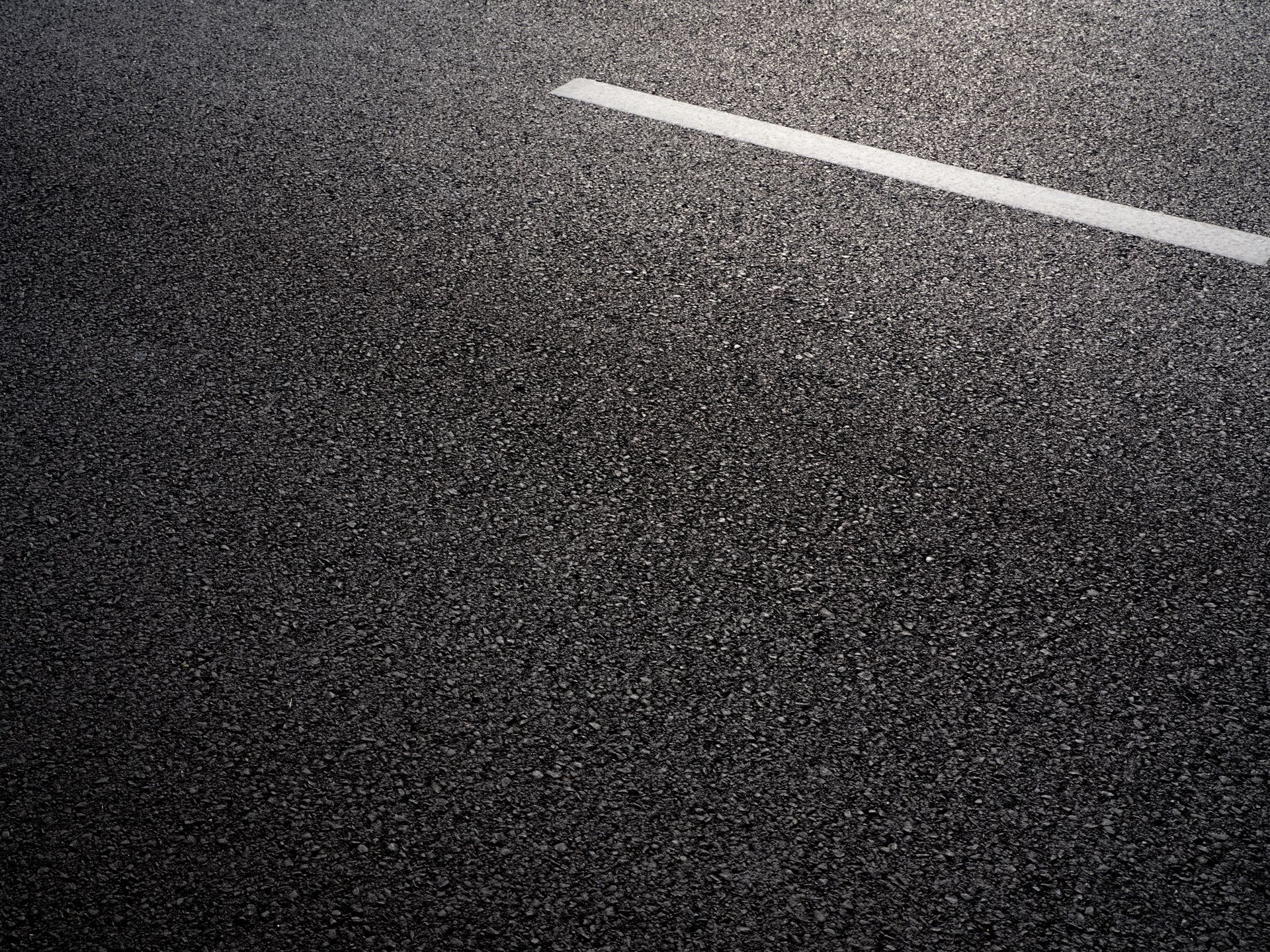 Black asphalt road with a white dividing line.