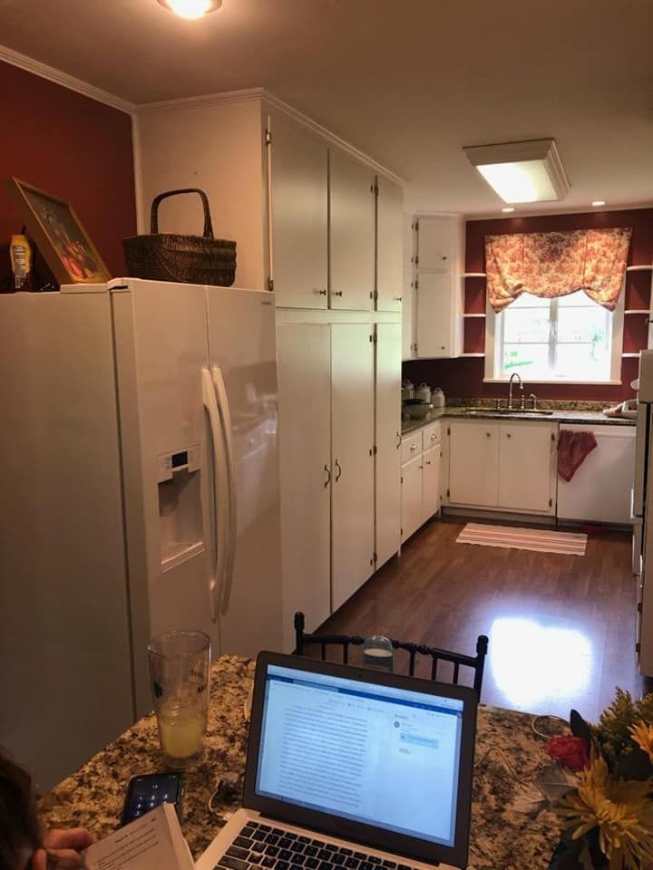 A laptop is sitting on a counter in a kitchen next to a refrigerator
