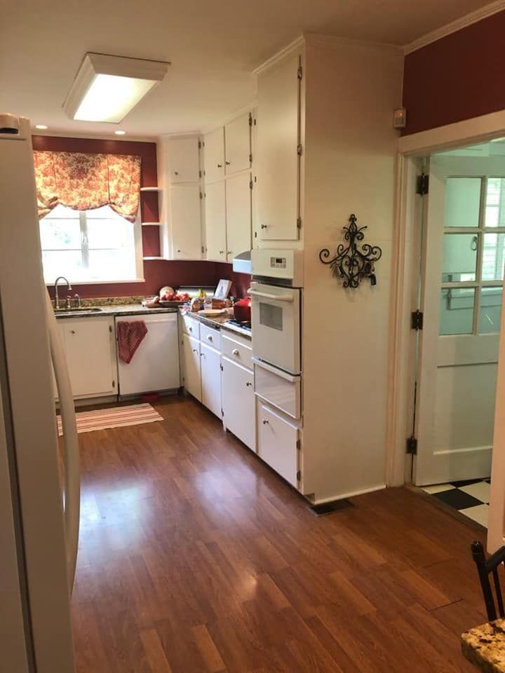 A kitchen with white cabinets and hardwood floors