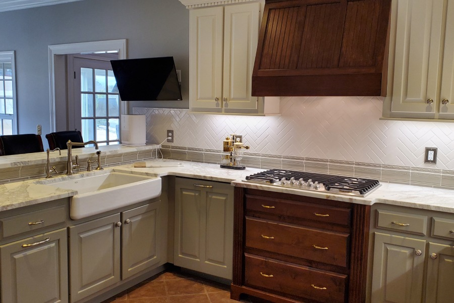 A kitchen with a stove , sink , and cabinets.