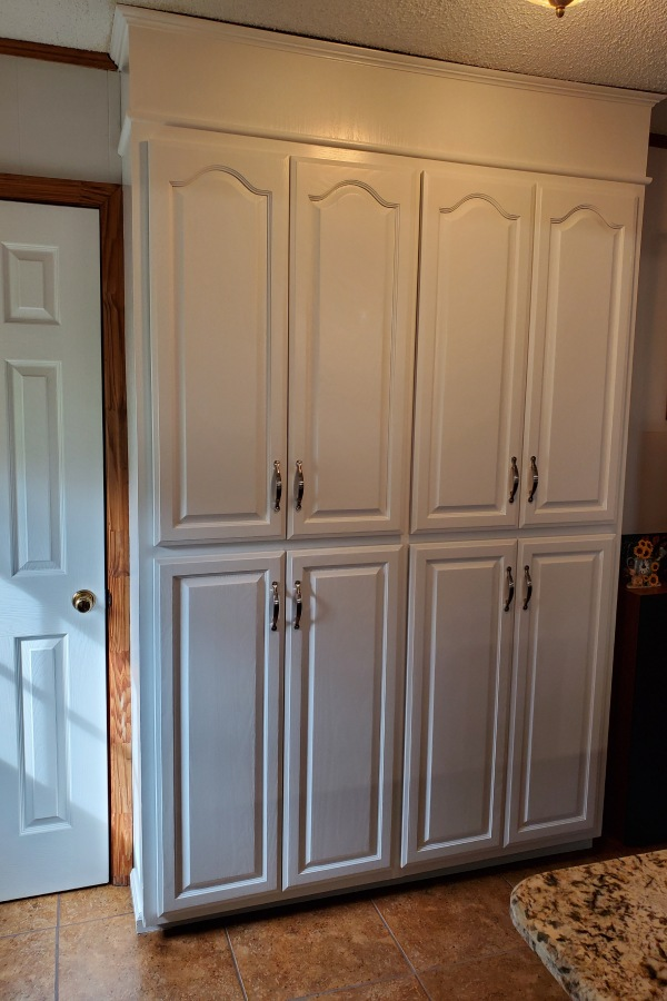 A kitchen with white cabinets and a white door.