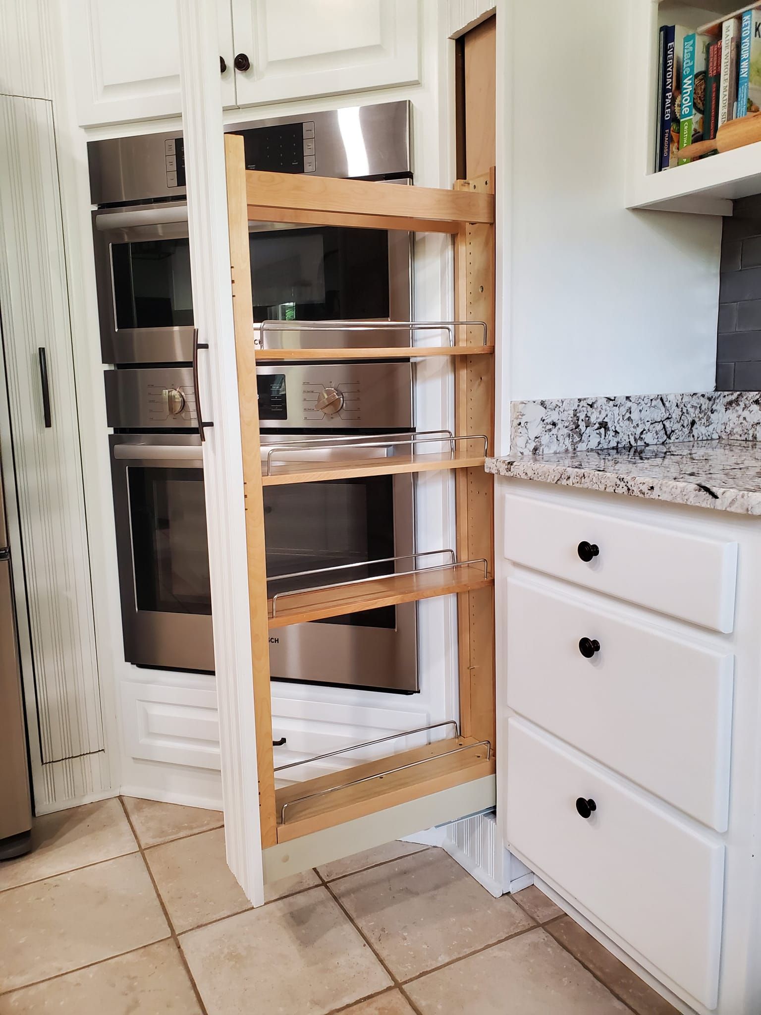 A kitchen with stainless steel appliances and a pull out pantry.