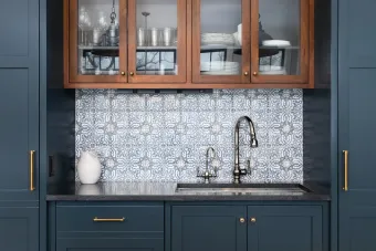 A kitchen with blue cabinets and a sink with a glass door.