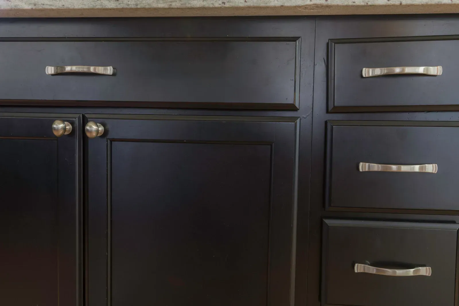A close up of a black cabinet with drawers in a kitchen.