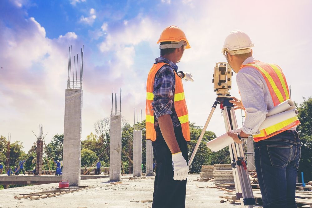 Two construction workers are standing next to each other at a construction site.