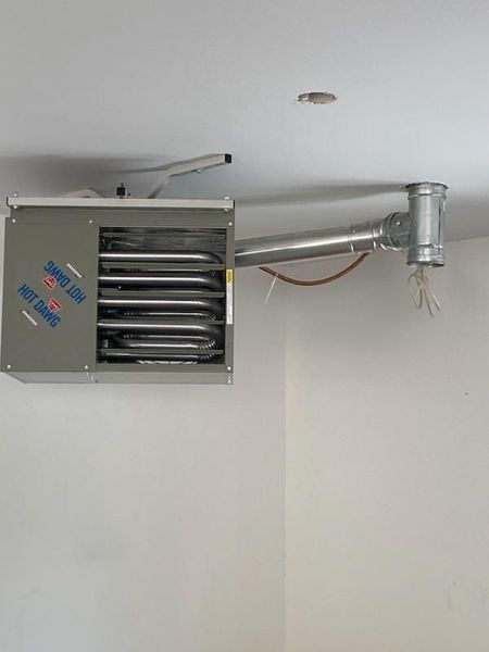 Ceiling-mounted propane heater with exhaust pipe in a white room.