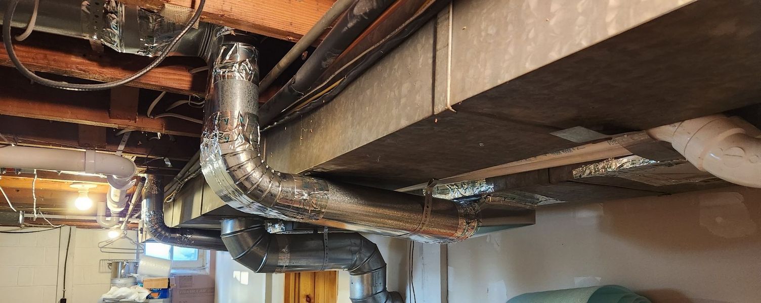 Basement with ductwork and plumbing pipes, some with condensation.