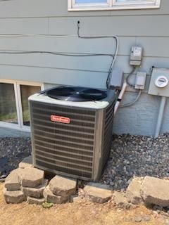 Goodman air conditioning unit outside a light blue house.