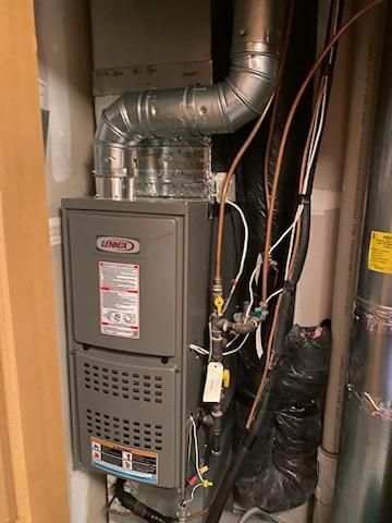 Gray Lennox furnace in a utility room with silver ductwork and gas lines.