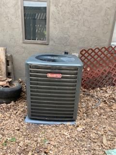 Goodman air conditioner unit outside a building, on a concrete pad.