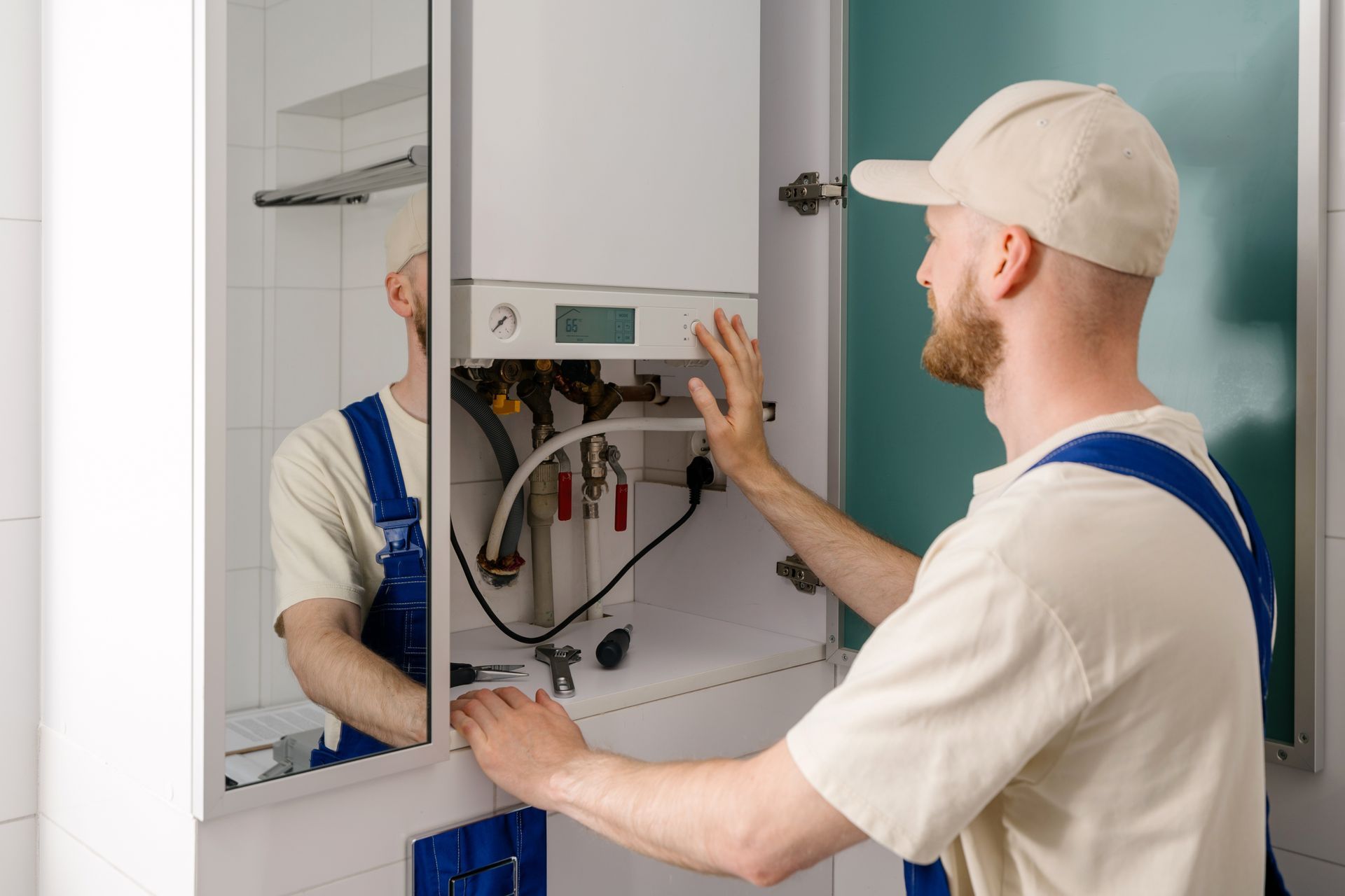 Repairman maintaining gas boiler in modern bathroom for efficient heating.