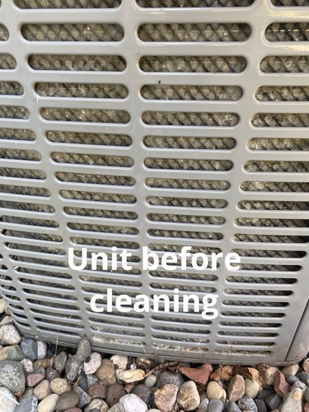 Close-up of an air conditioning unit before cleaning. The unit is grey and covered in dirt.