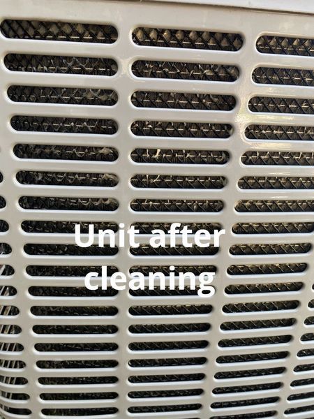 Close-up view of a cleaned air conditioning unit with a white, slotted metal grill.