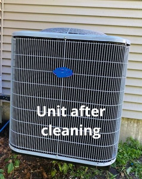 Air conditioning unit after cleaning, featuring a dark metal grill and a blue logo. Next to a light-colored building.