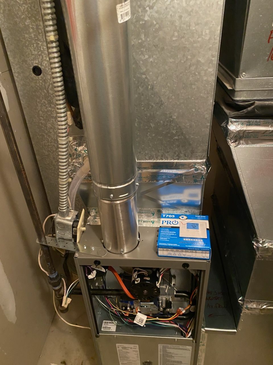 Vacuum pump on a ladder, connected to an AC unit being serviced by a technician outdoors.