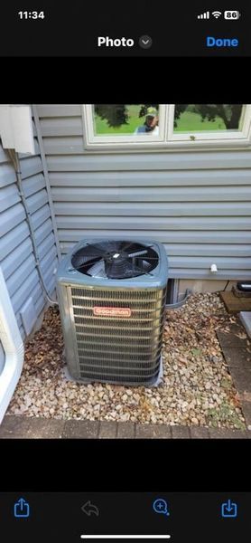 Air conditioning unit outside a house, surrounded by gravel.